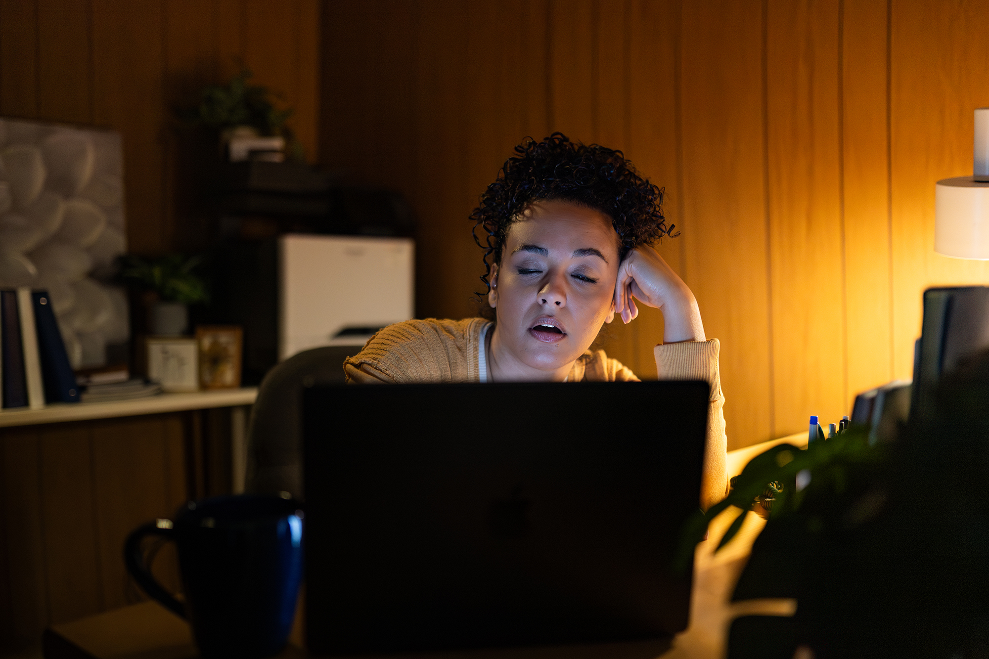 Small business owner falls asleep at her laptop after hours of trying to learn marketing tools